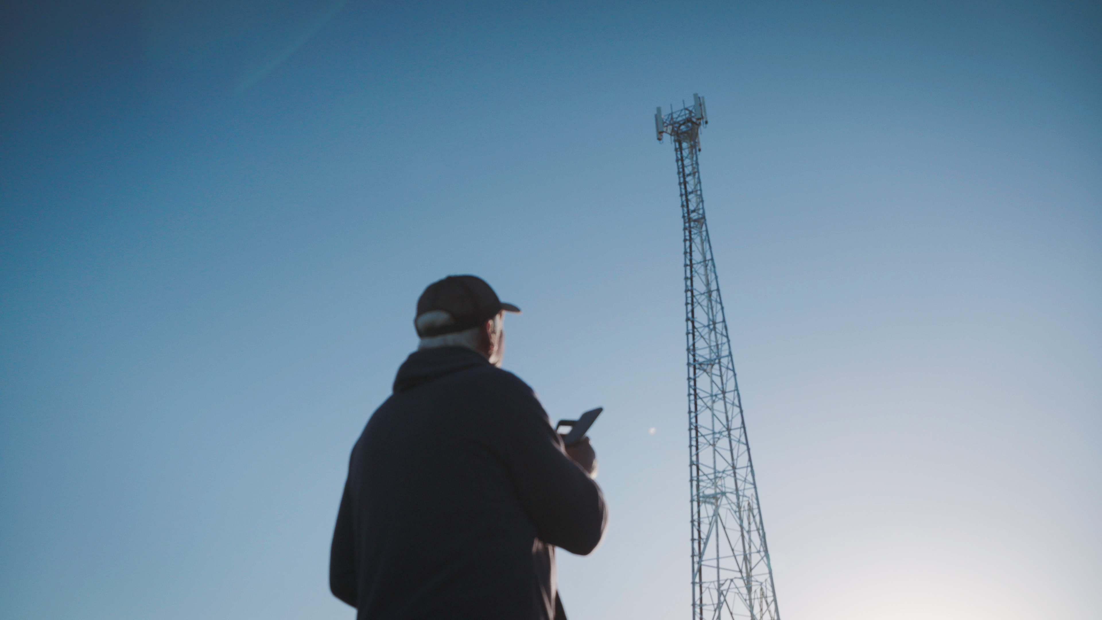 Telstra Blue Tick man on phone looking at regional network tower