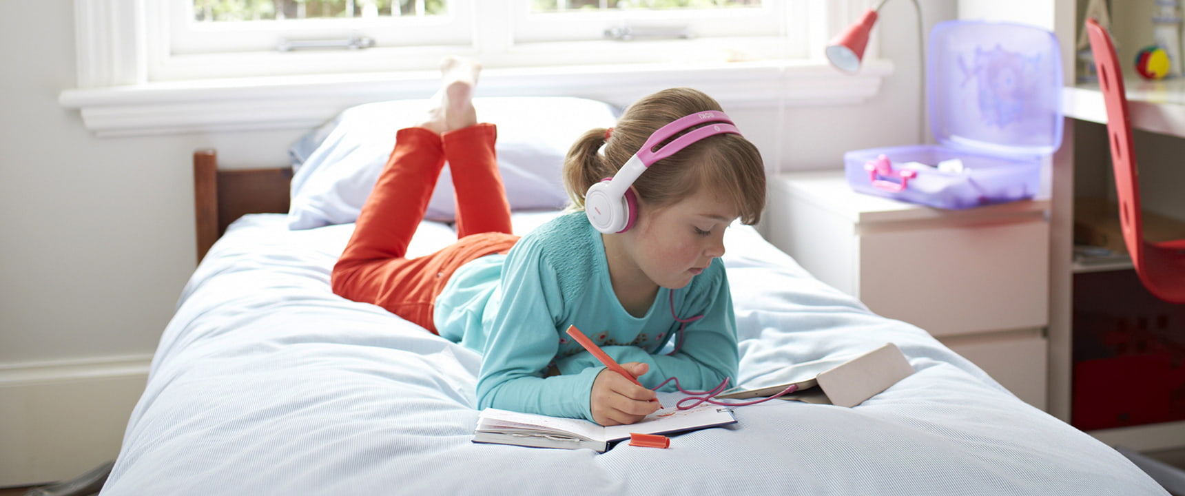 Young girl on her bed watches iPad with headphones using Telstra ADSL internet