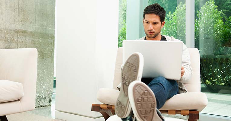 Man relaxing with feet up and a laptop on his knee