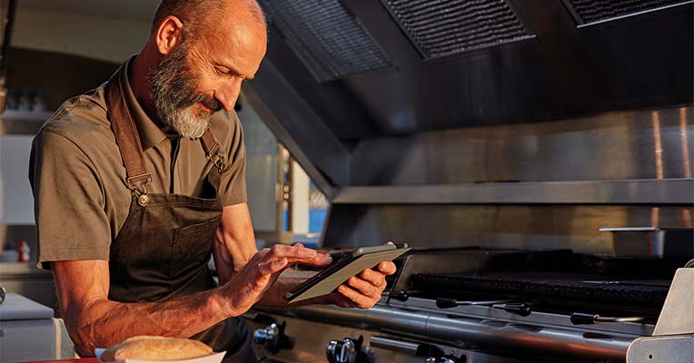 Man in food truck using a hand held tablet