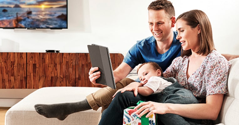 Young family sitting on the couch engaging with a tablet device