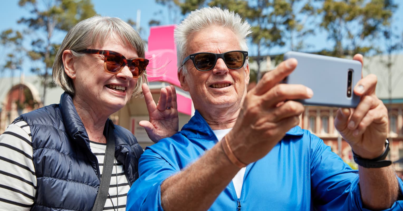 Elderly couple outdoors taking a photo with their phone