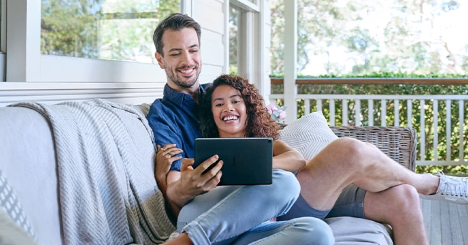 Man and woman sitting outside engaging with a tablet device