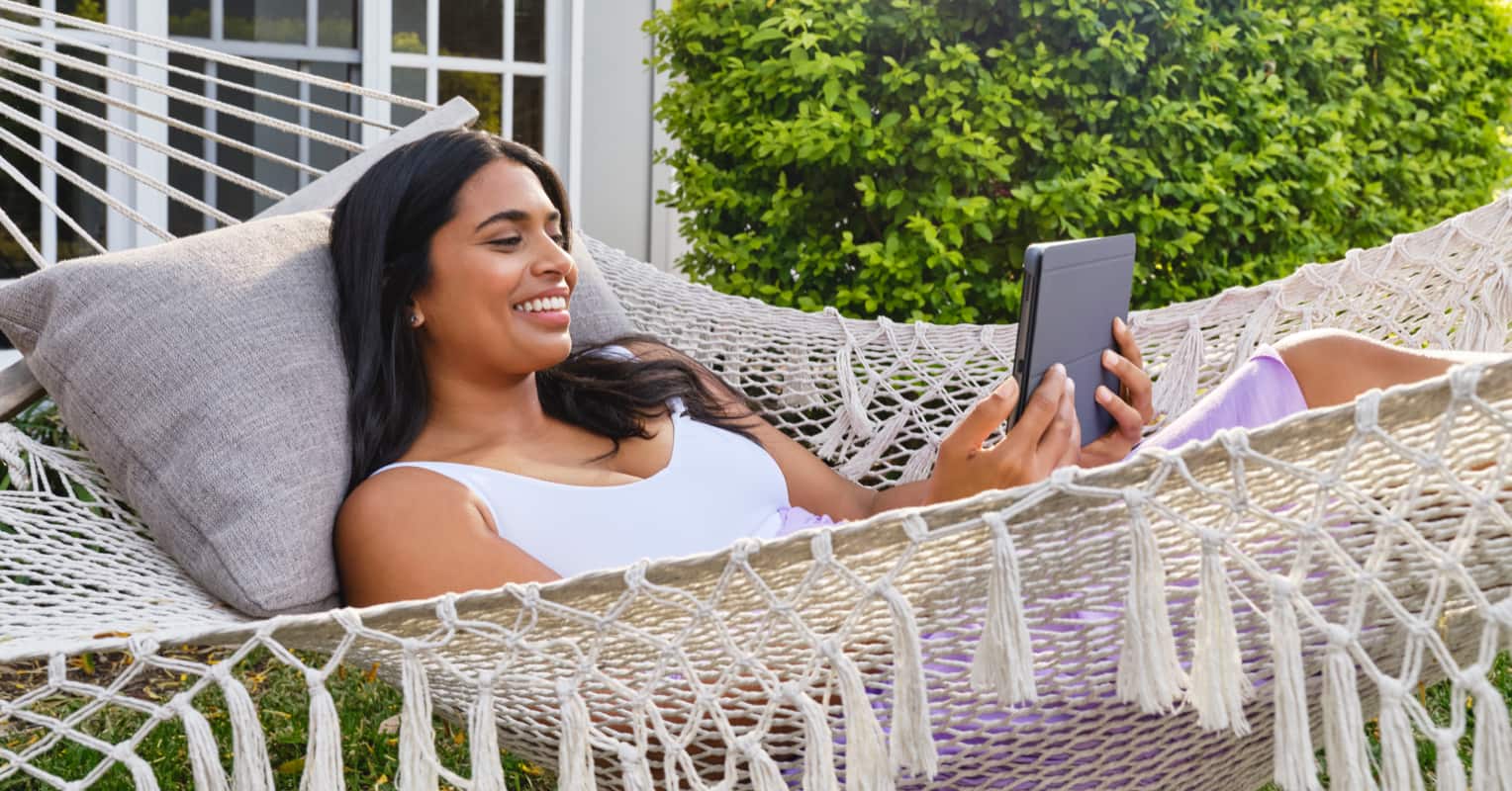 Person sitting in a hammock using a tablet device