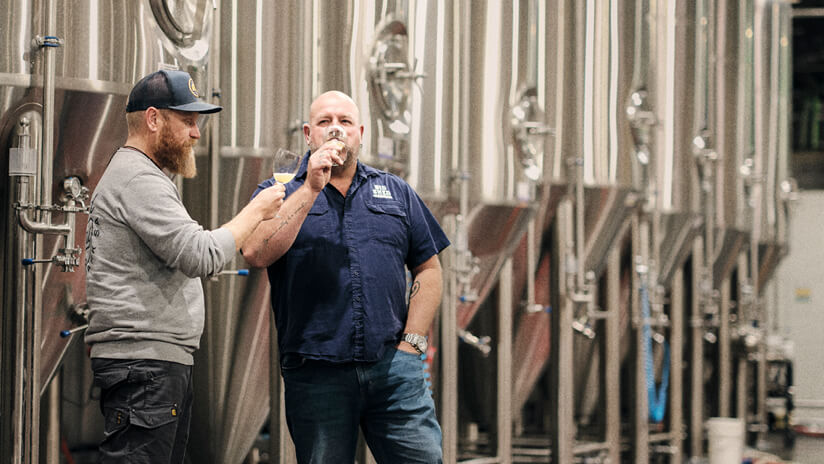 Founders of Big Shed Brewing, Craig Basford and Jason Harris, sip drinks in their brewery