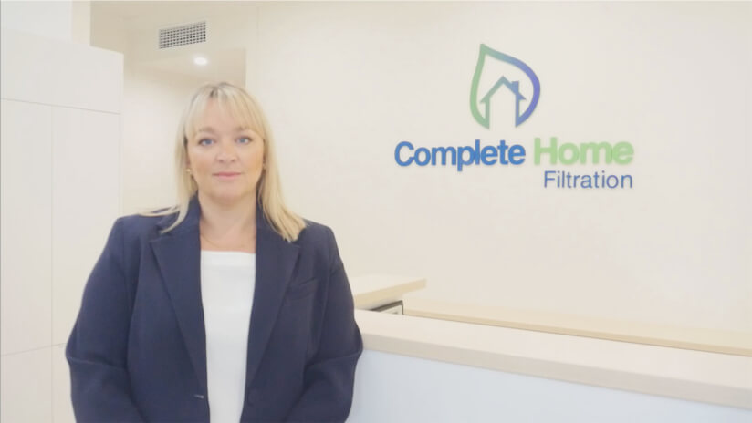 Complete Home Filtration founder, Suzanne Dodds stands in front of the company logo