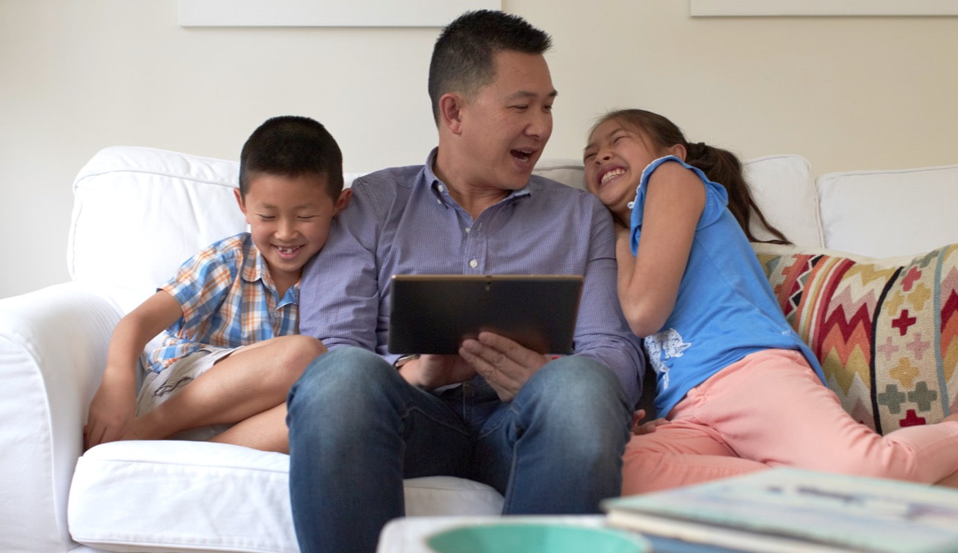 A happy family look at an iPad together at home.