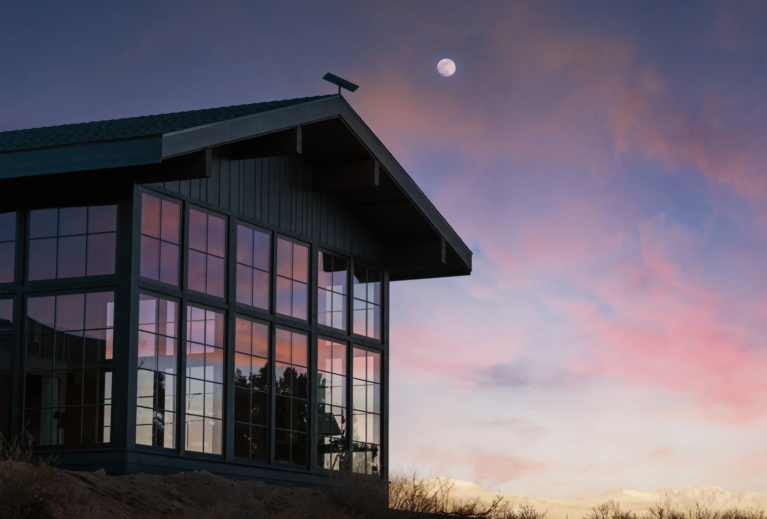 Starlink antenna mounted  on a roof beneath a full moon  and a dusky-pink sky.