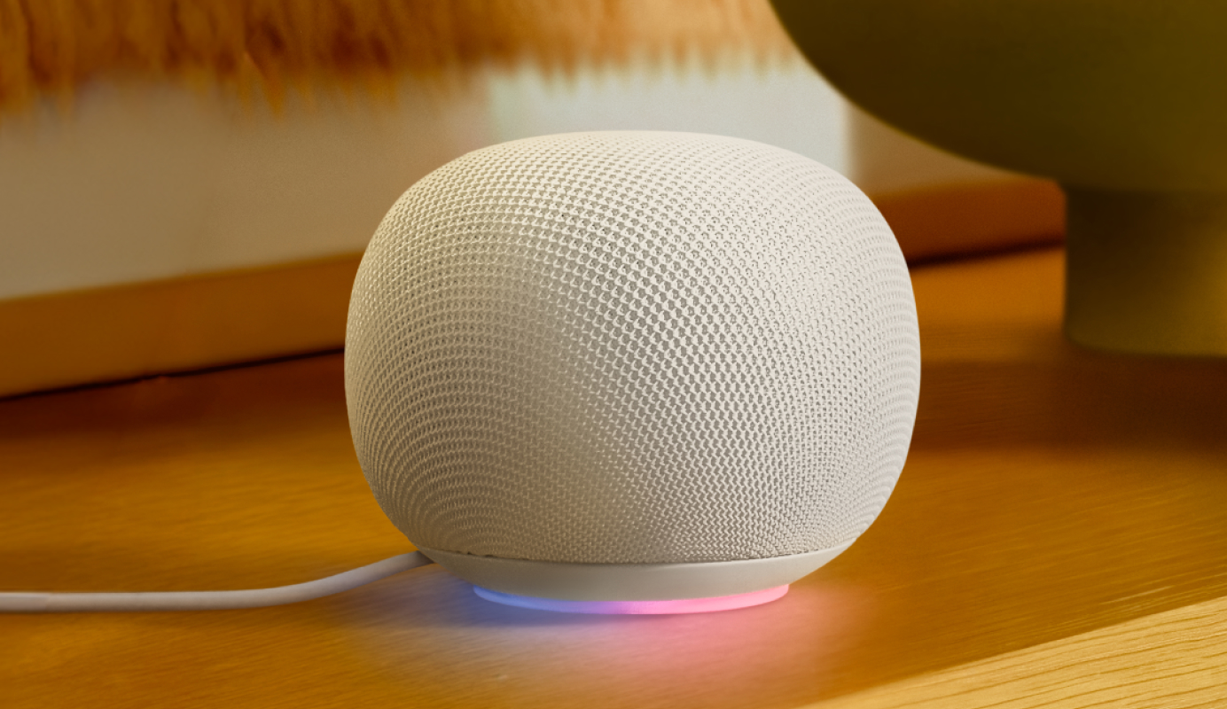 A Google Nest Hub Max rests on a side table displaying time of day, the weather and a beautiful, sharp sunset image as wallpaper.