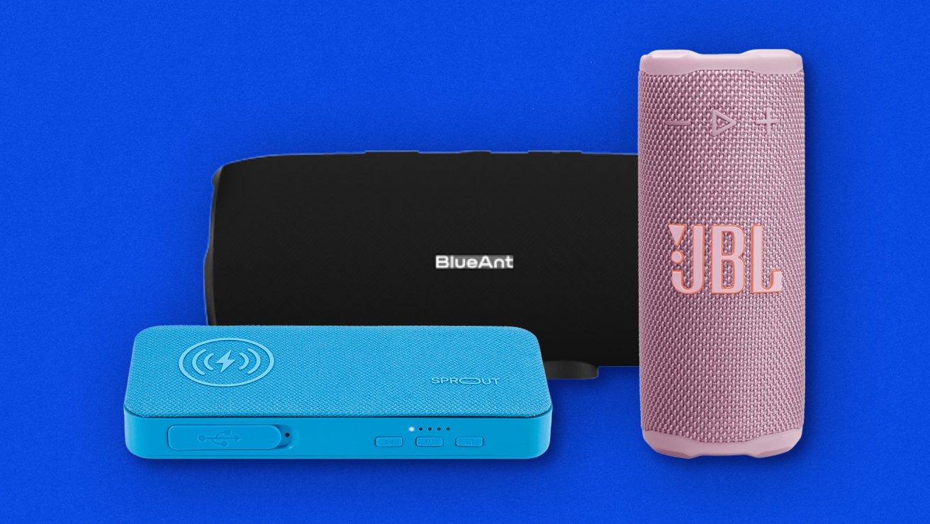 Flat lay of accessories. Front view of black BlueAnt X3i Bluetooth speaker in background. Front view of blue Sprout Maverick Hybrid 2 3-in-1 speaker in foreground to left, and front view of pink cylindrical portable JBL Grip Bluetooth Speaker.