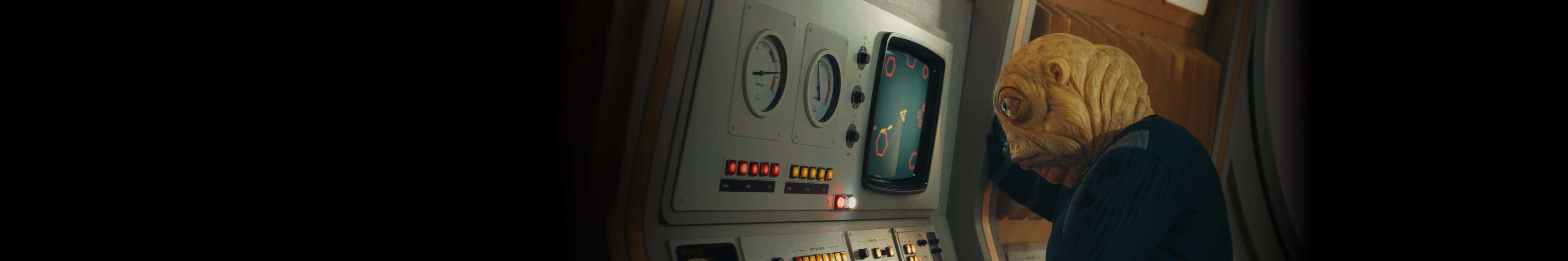 A key villain, Evil Brian, stands in front of a control panel playing a 70’s-style spaceship game.