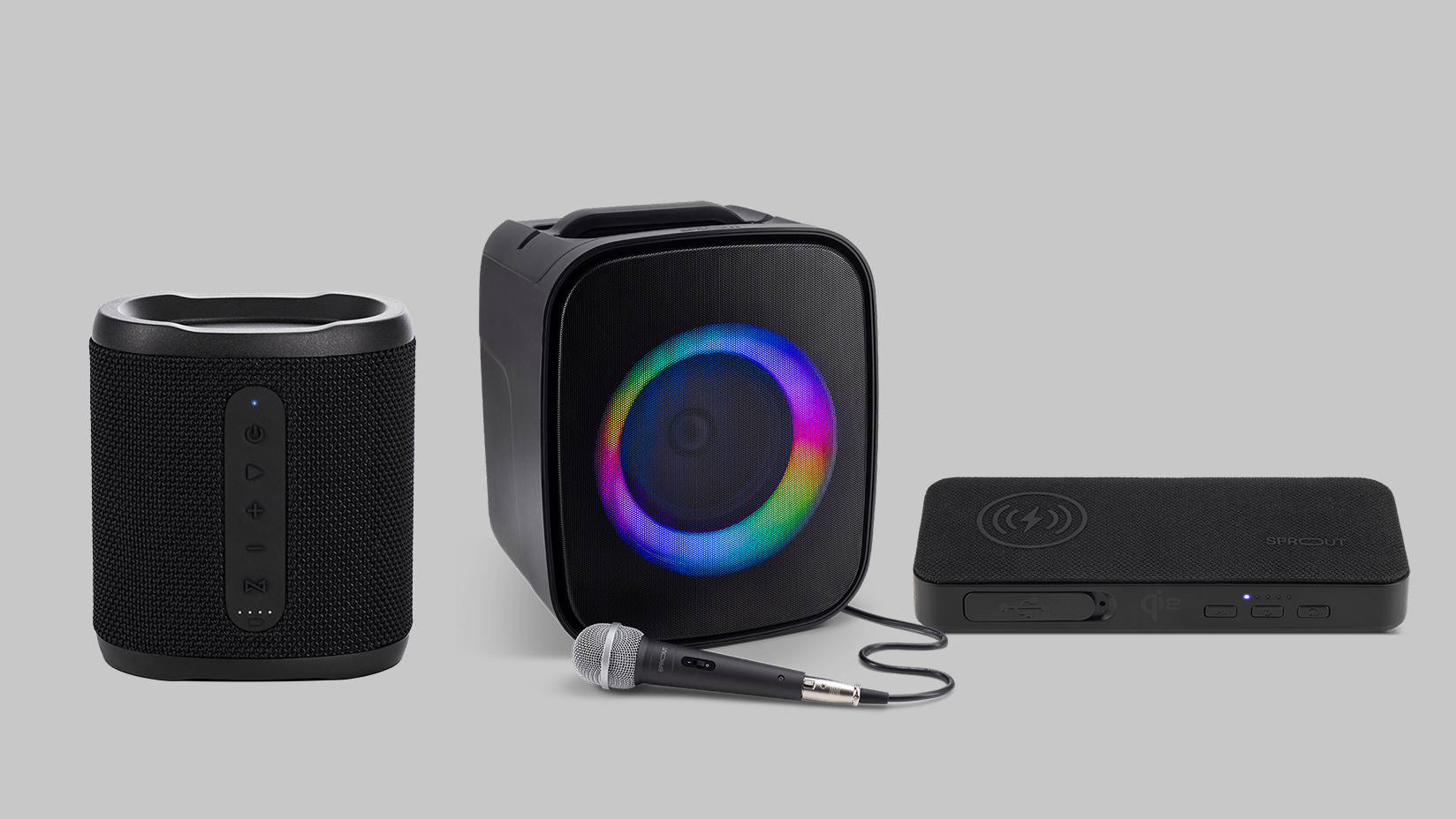 Three speakers are pictured beside each other. On the left is the Soundwave Lite Bluetooth speaker, cylindrical with a mesh exterior and front-facing control buttons. In the centre is the Soundloop Party Speaker, a larger boxy unit with a colourful LED ring around the speaker and a wired microphone placed in front. On the right is the Maverick Hybrid 2 3-in-1 Bluetooth speaker, flat and rectangular with wireless charging symbols and control buttons on its surface.