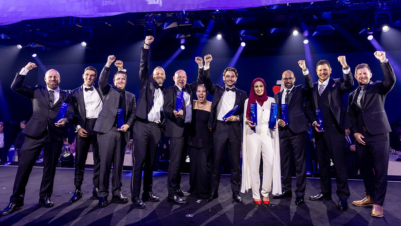 National Winners standing in a line on stage with their arms held up in celebration of their award win.