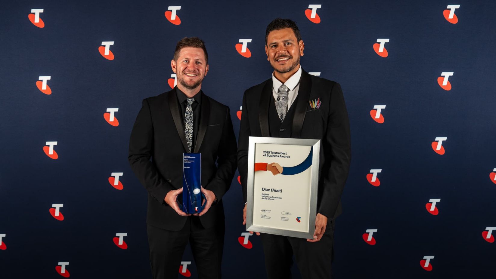 Ray and Lindsay are smiling, holding their award and award certificate.