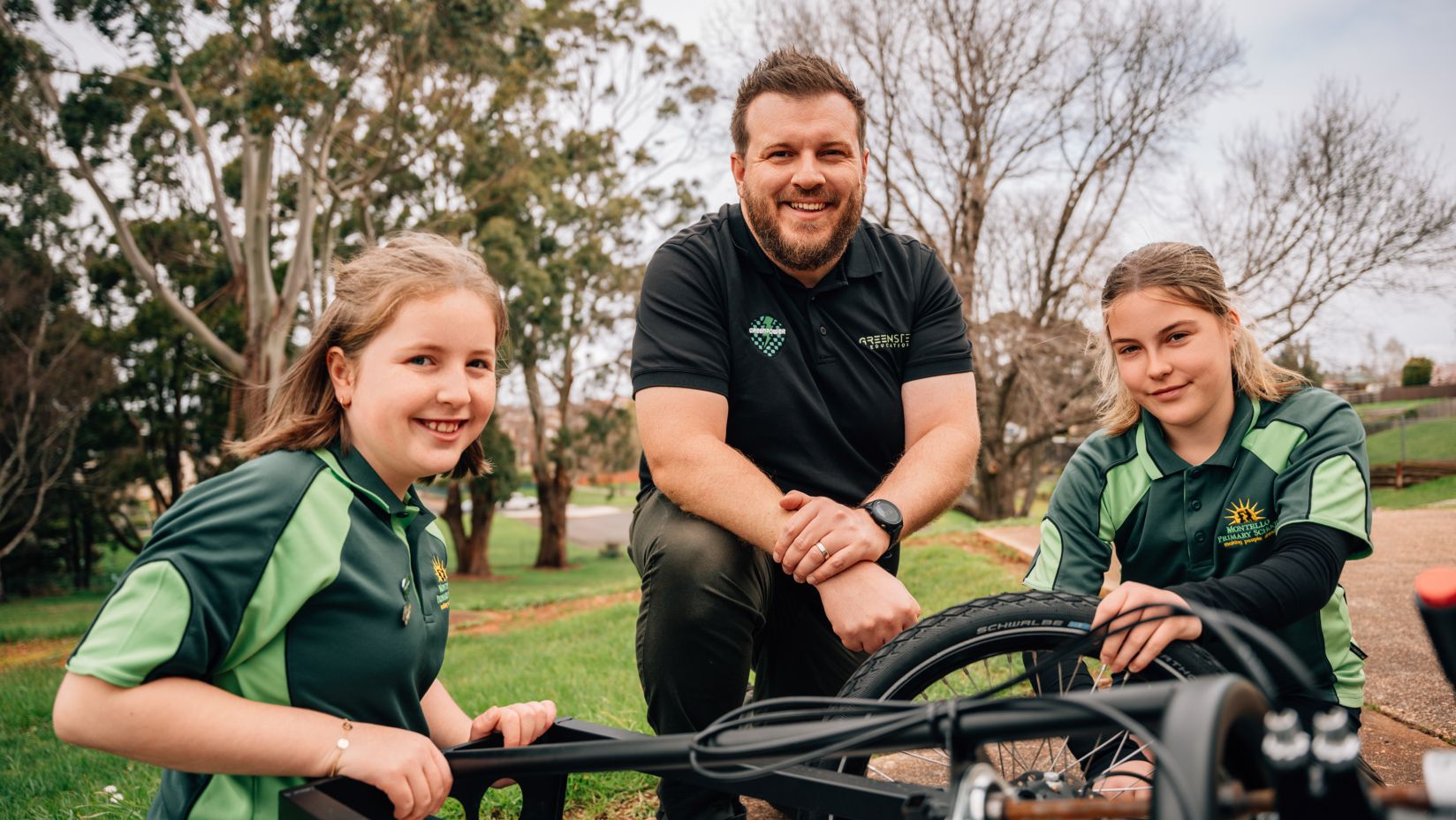 Daniel and his students are smiling crouched around their electric vehicle.