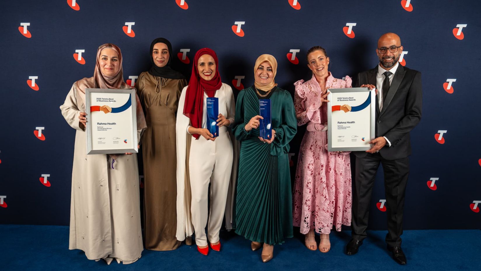 Naba and the Rahma Health team are smiling, holding their award and certificates.
