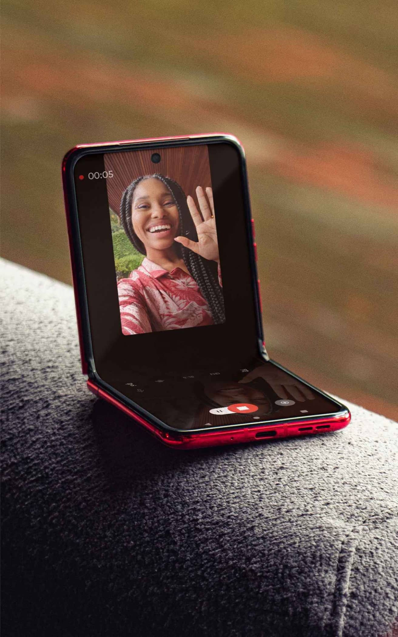 A motorola razr 40 ultra is flipped open to 90 degrees and rests on the arm of a chair. A video call is depicted on screen.