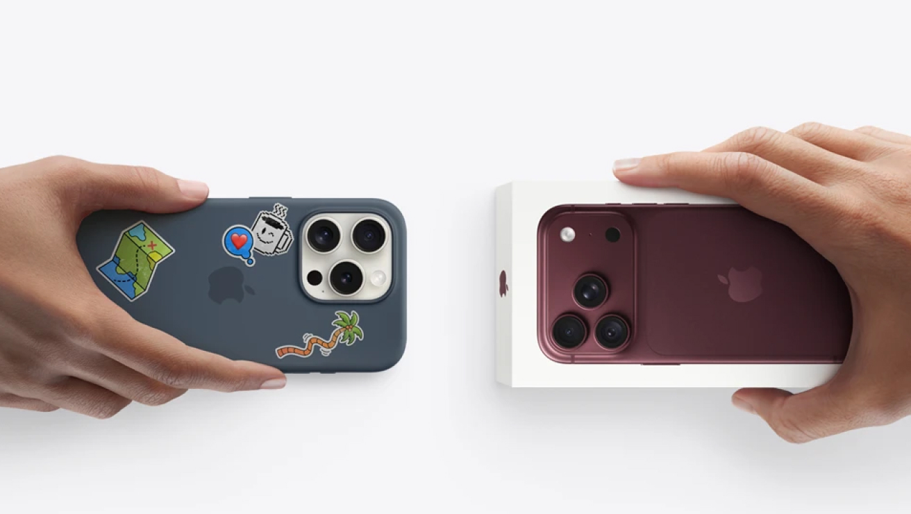 Someone holding their iPhone, in a case covered in stickers, towards a iPhone 18 Pro box.