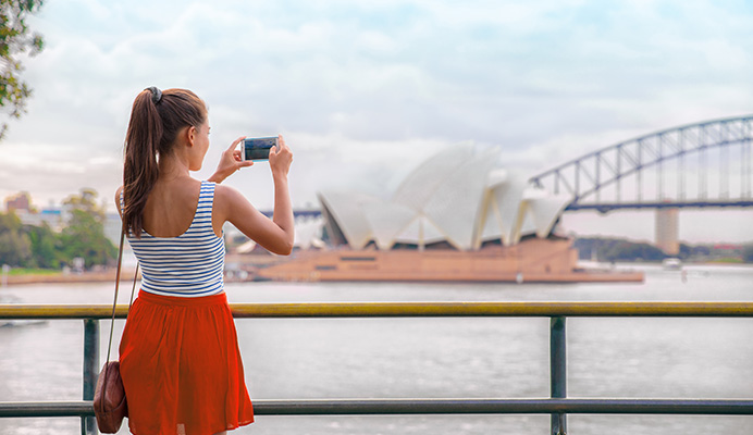 Woman taking a photo of the Opera House.