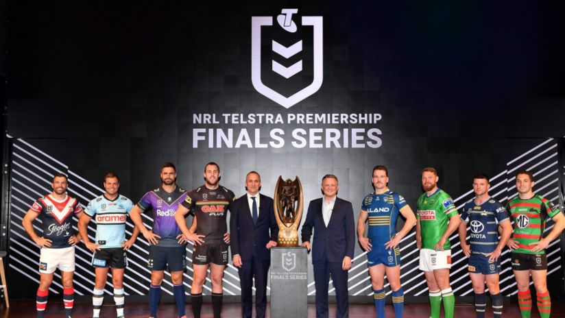 NRL team captains lined up on a stage with the 2022 NRL Grand Final trophy