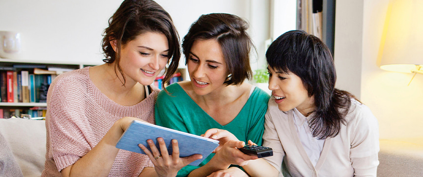 3 young women smiling at a tablet